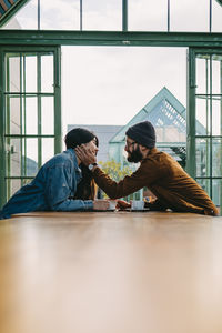 Side view of couple sitting on window