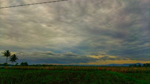 Scenic view of field against storm clouds