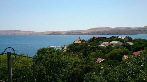 Scenic view of sea in front of town against clear blue sky