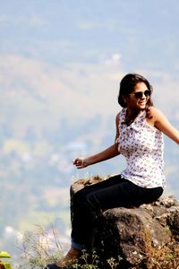 Happy young woman sitting on rock