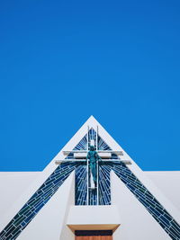 Low angle view of rollercoaster against clear blue sky