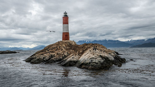 Lighthouse by sea against sky