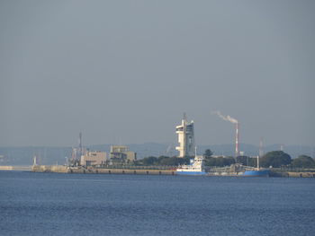 View of factory by sea against clear sky