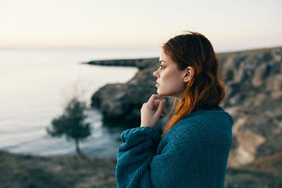 Young woman standing by sea against sky