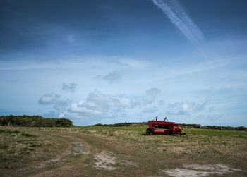 Car on road amidst field against sky