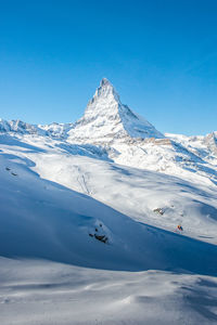 Scenic view of snowcapped mountains against blue sky