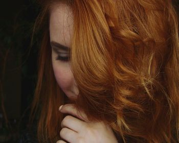 Close-up of beautiful redhead young woman against black background