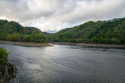 Scenic view of river by mountains against sky