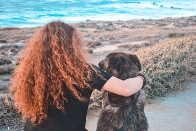 Rear view of woman with dog on beach