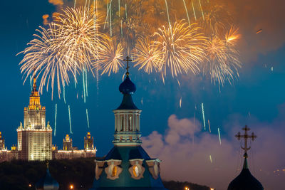 Firework display over building against sky at night