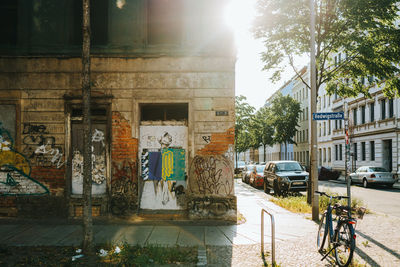 Graffiti on building by street in city against sky