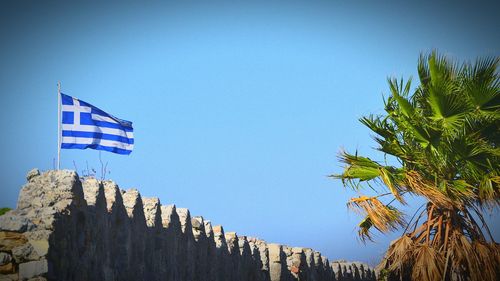 Low angle view of flags against clear blue sky