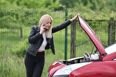 Full length of woman standing against car