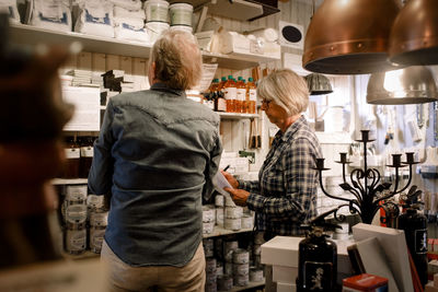 Senior coworkers examining merchandise arranged on shelves in hardware store