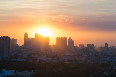 Buildings in city against sky during sunset