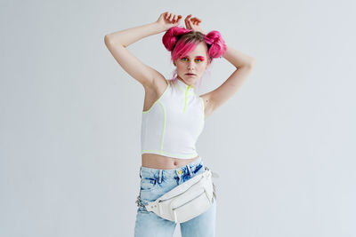 Rear view of woman with arms raised standing against white background