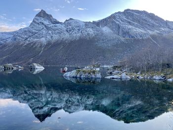 Scenic view of lake by snowcapped mountains against sky