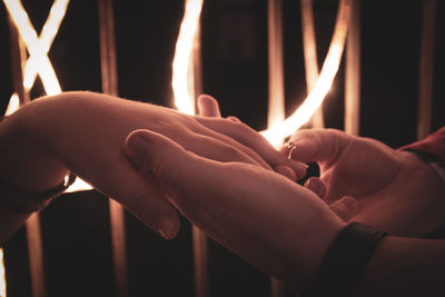 Close-up of hands holding lit candles