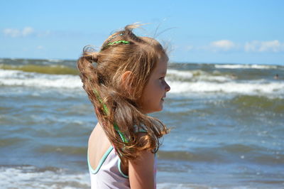 Side view of girl at beach against sky