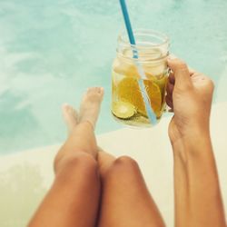 Woman holding refreshing drink by swimming pool