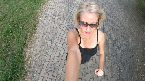 Woman taking selfie while jogging on footpath