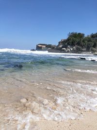 Scenic view of beach against clear blue sky