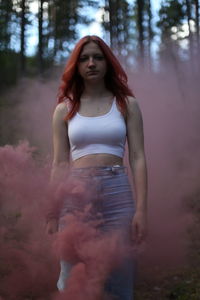 Portrait of young woman standing against wall