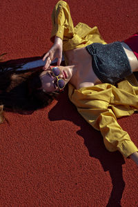 High angle portrait of woman wearing eyeglasses lying on running track