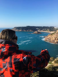 Rear view of woman on shore against clear blue sky