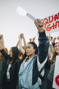 Low angle view of women holding hands while protesting for human rights against sky