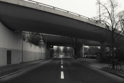 Road by bridge in city against sky