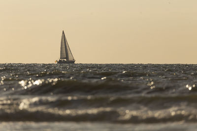 Sailboat sailing on sea against sky during sunset