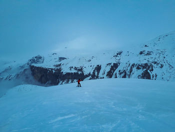 People skiing on snowcapped mountain against clear blue sky