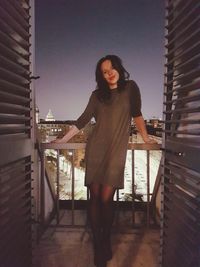 Portrait of woman standing against railing at home