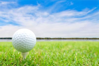 Close-up of golf ball on field against sky