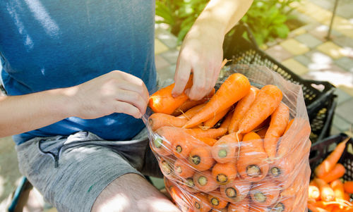 A farmer is packing freshly picked carrots into bags for sale. freshly harvested carrots. 