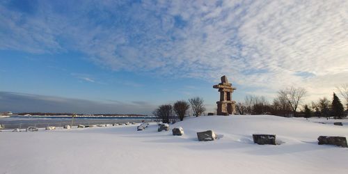 Snow covered landscape by sea against sky