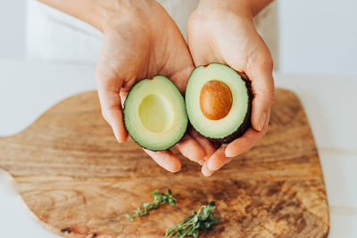 Close up of hands holding fresh avocado, source of healthy fats