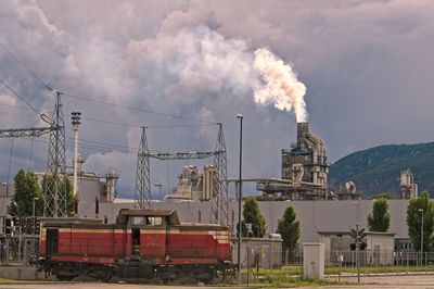 Smoke emitting from factory against sky