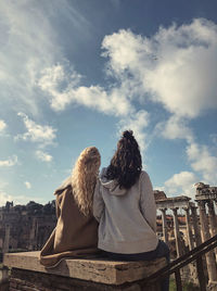 Rear view of woman with umbrella on railing against sky