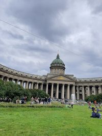 Group of people in front of building against cloudy sky