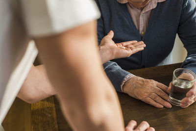 Hand of young man giving senior man his tablet