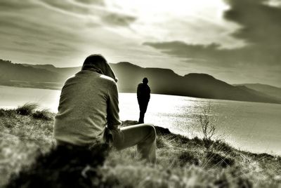 Rear view of people on mountain by sea against sky