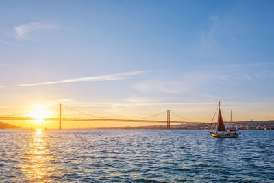 Suspension bridge over river against sky during sunset