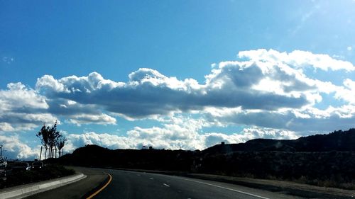 Empty road against cloudy sky