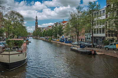 Sailboats moored on canal in city against sky