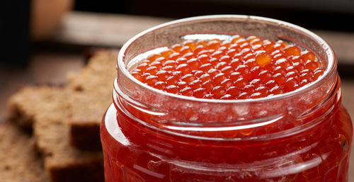 Full glass jar with red caviar on a brown wooden table, top view