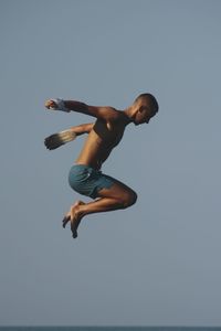 Low angle view of man jumping against clear sky
