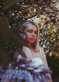 Portrait of young woman against flowering plant