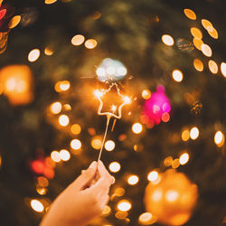 Cropped hand holding illuminated string lights